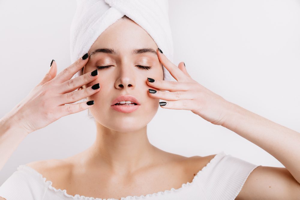 adult woman with healthy skin massages her face prolong youth snapshot girl after shower isolated wall - پوستی درخشان